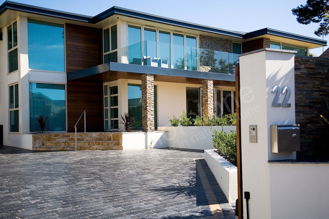 Exterior of a residential home with a modern design scheme prominently featuring glass, steel, and stone